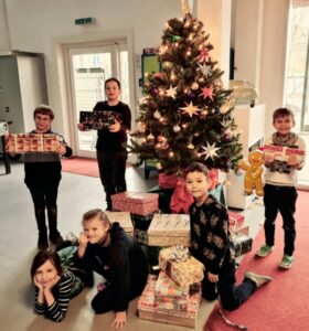 Schüler:innen mit Humedica Geschenken vor dem Weihnachtsbaum.