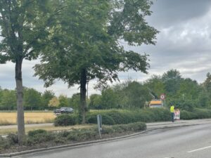 Ein Gelände mit einem Baufahrzeug im Hintergrund und einer Straße im Vordergrund.