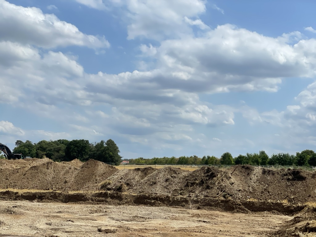 Erdhaufen hinter eine Fläche von der die Erde abgetragen wurde.
