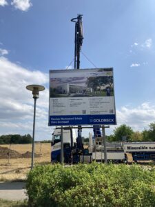 Die Bautafel wird mit einem Kran aufgestellt.