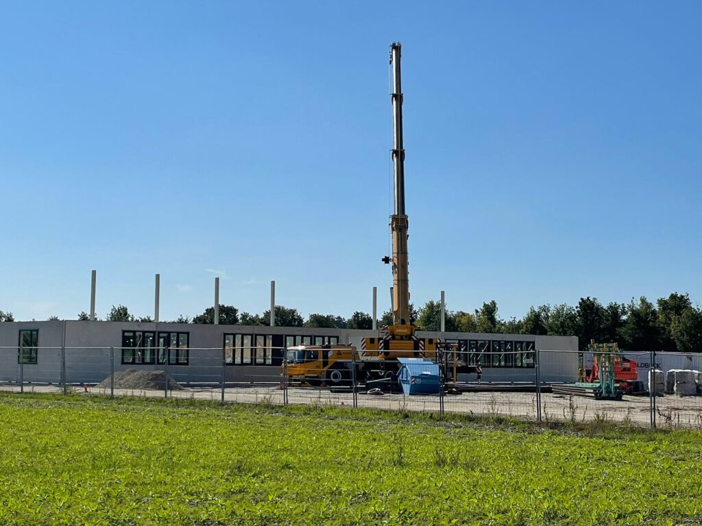 Neubau 28.09.2023 Ein Kran stellt wände auf und eine ganze Reihe Wandteile steht schon.