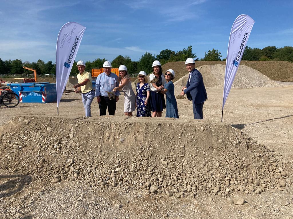 Vertreter:innen von Schule, Stadt und Baufirma beim gemeinsamen ersten Spatenstich mit Spaten in der Hand.
