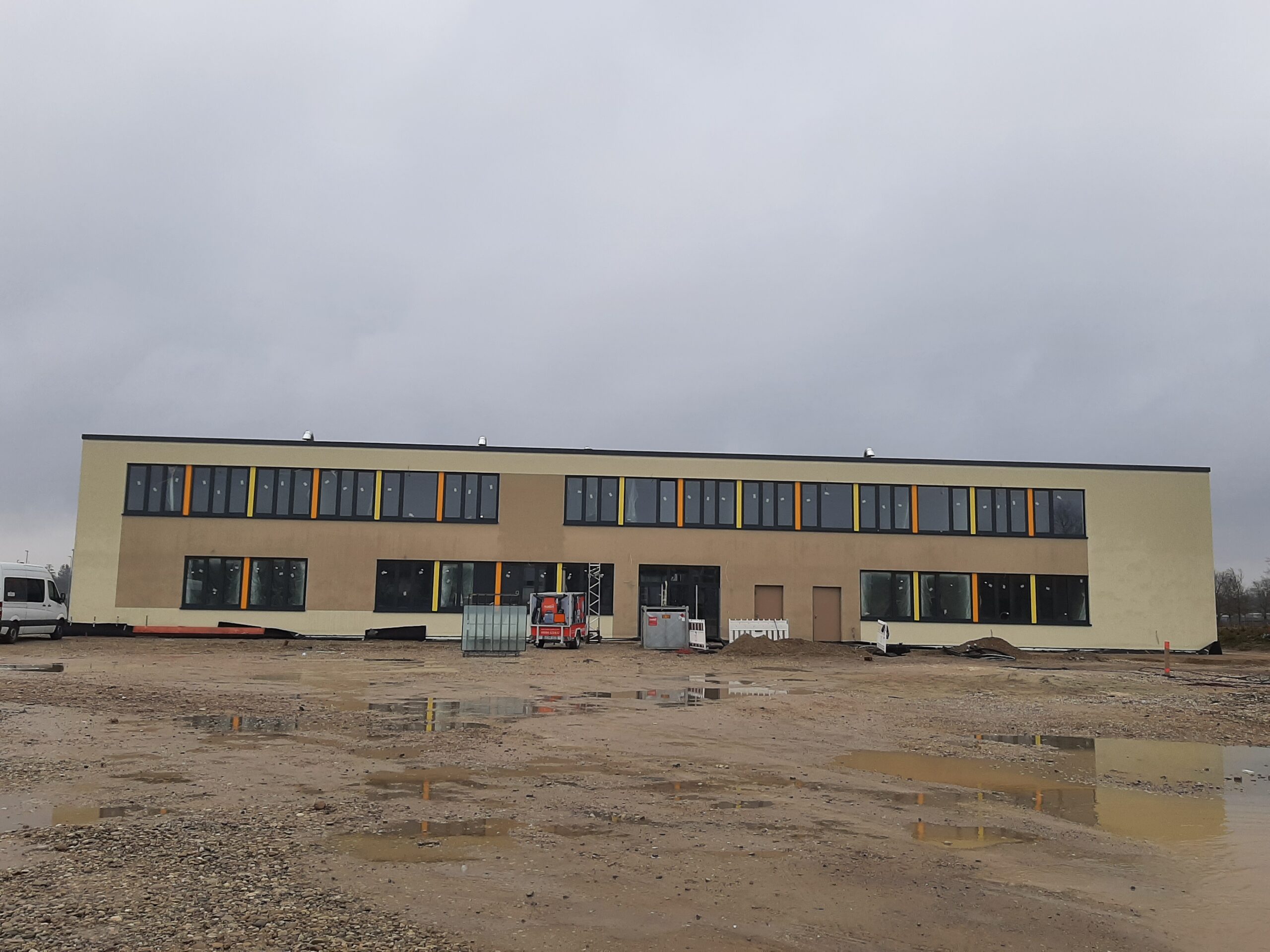 Ansicht des neuen Schulgebäues mit viel Matsch rundherum.